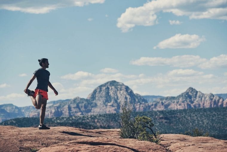man stretching in front of a mountain backdrop