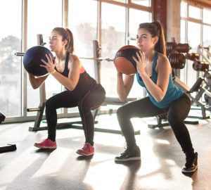 a pair of women exercising with a ball
