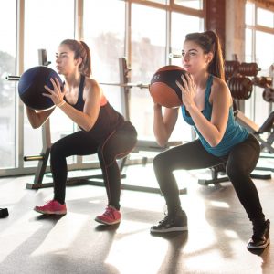 a pair of women exercising with a ball