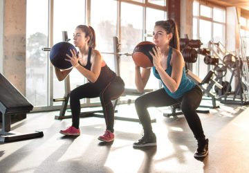a pair of women exercising with a ball