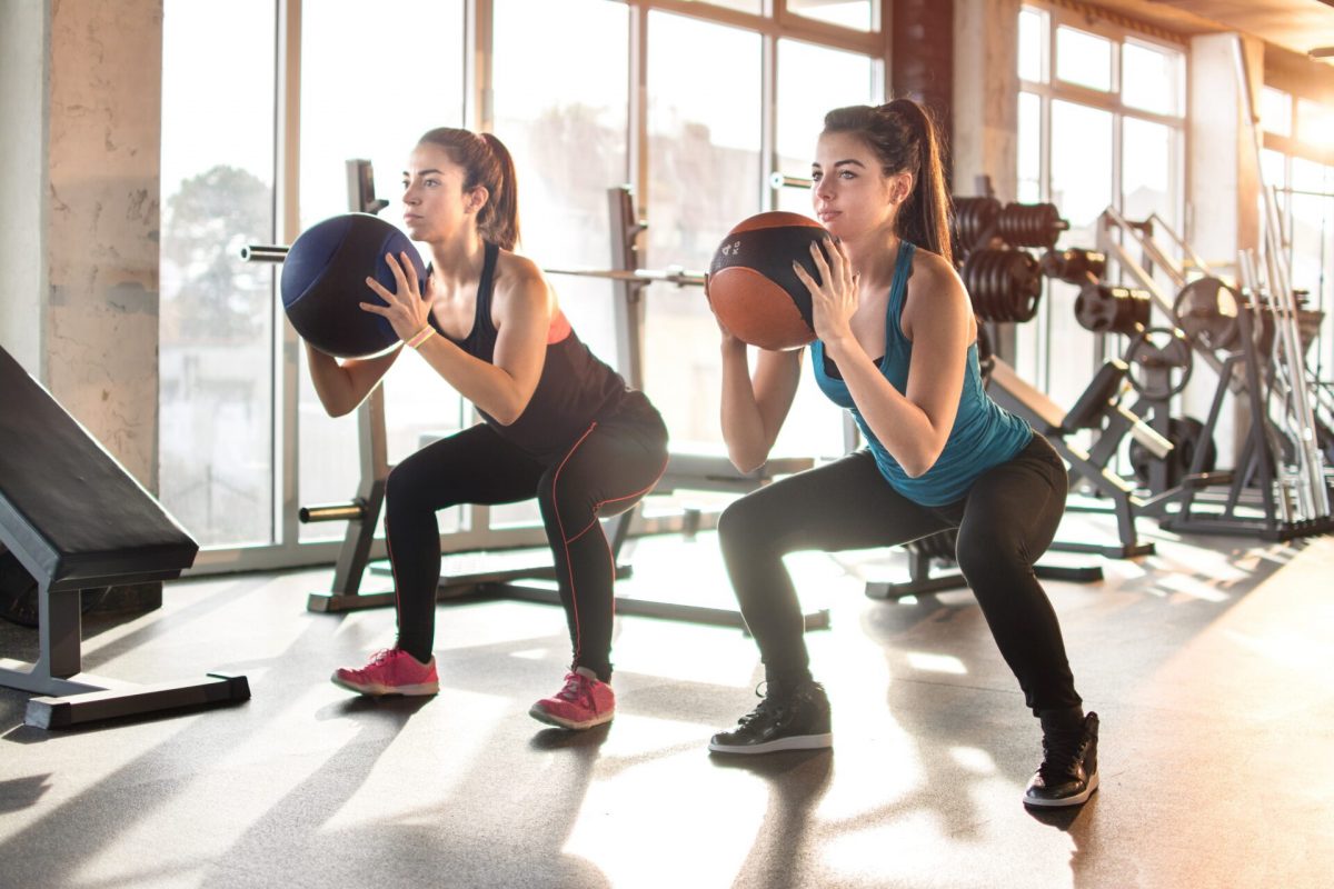 a pair of women exercising with a ball