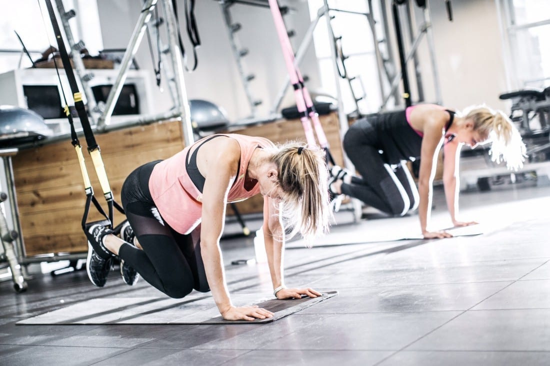 a pair of women doing core exercises in the gym