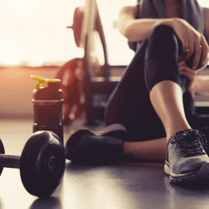 a woman seated on the floor in the gym surrounded by gym equipment