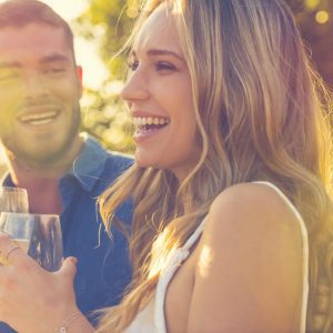 a couple outdoors on a sunny day enjoying a glass of wine