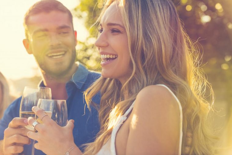 a couple outdoors on a sunny day enjoying a glass of wine