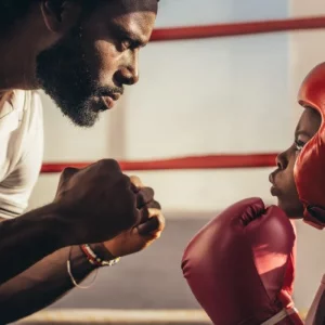 a boxing coach and a young student staring at each other