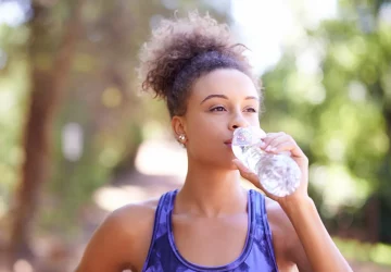 a healthy woman outdoors drinking water