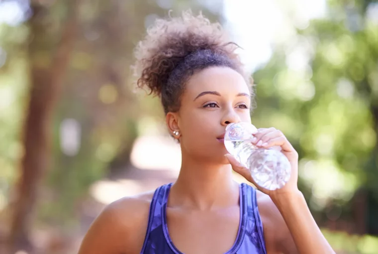 a healthy woman outdoors drinking water