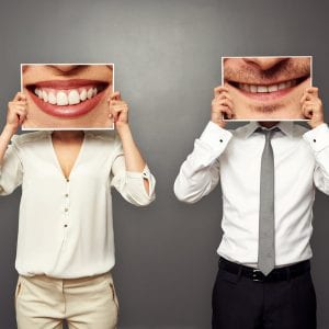 couple holding photos of big smiles