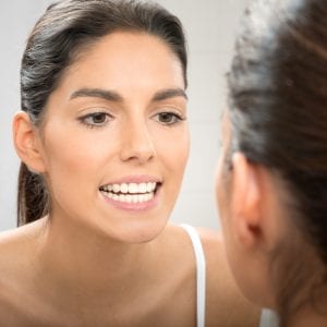woman inspecting her teeth in the mirror