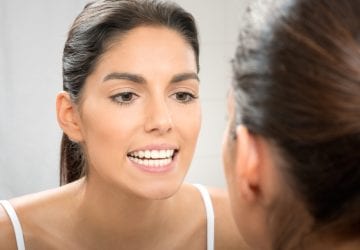 woman inspecting her teeth in the mirror