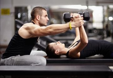 Man helps woman lifting weights