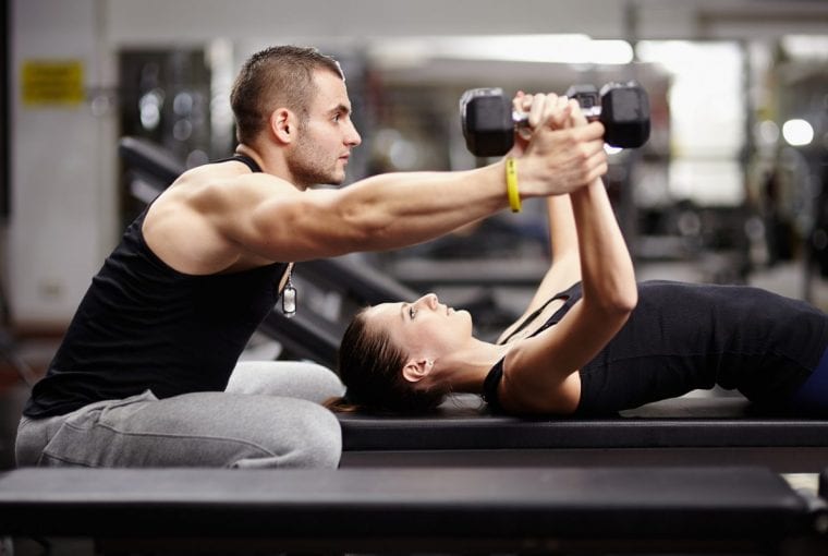 Man helps woman lifting weights