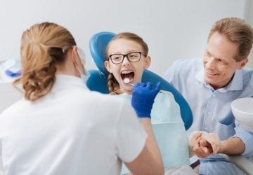 young girl having her teeth examined by her dentist