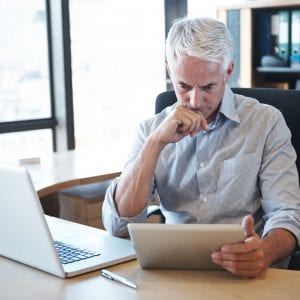 man reading tablet working at his desk
