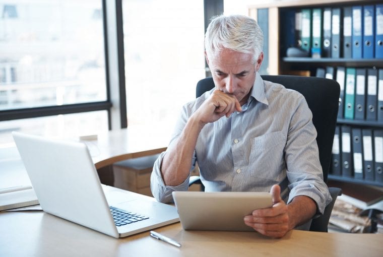 man reading tablet working at his desk