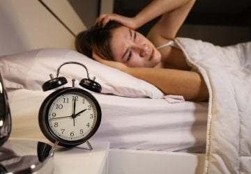 woman waking up with clock showing 2am