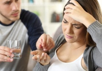 man giving medication to a woman for her headache