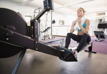 woman with towel around her neck on a rowing machine