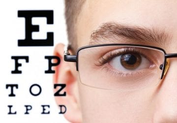 boy wearing glasses in front of an eye chart