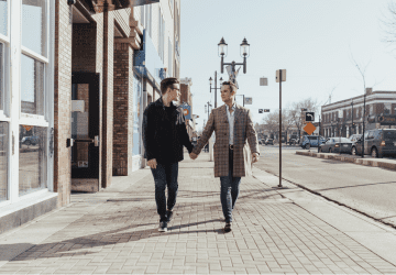 gay couple holding hands walking down a street