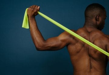 man stretches band across muscular back