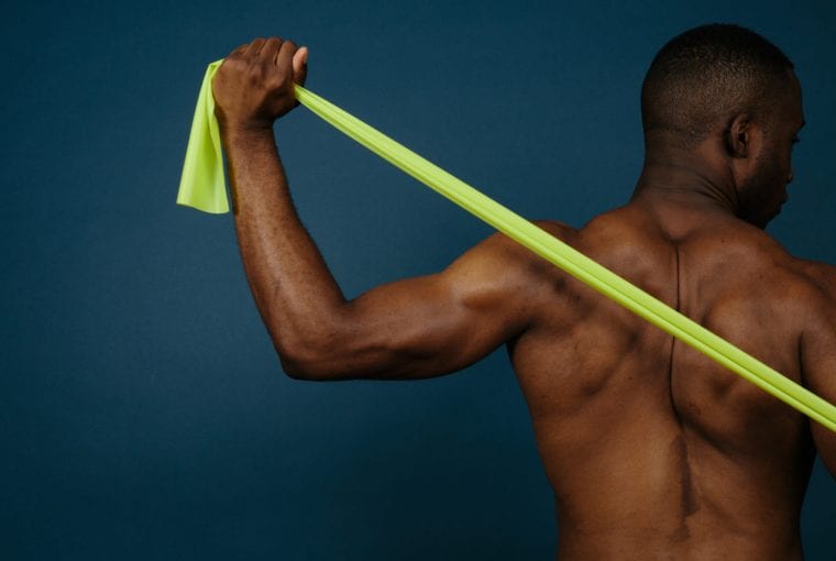 man stretches band across muscular back