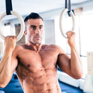 fit man doing pull-ups on rings
