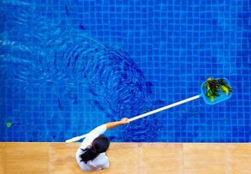 person cleaning debris out of a pool