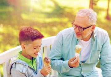 old man and boy eating ice cream at summer park