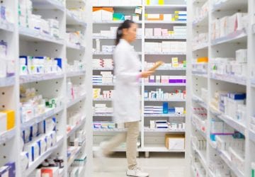 pharmacist walking in front of medicines