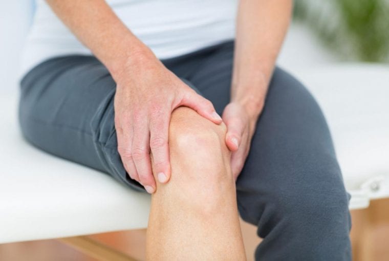 person sitting on a table holding their knee