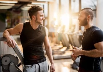 two men talking to each other at the gym