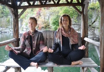 a pair of women meditating while sitting outdoors