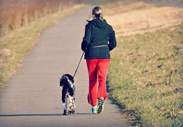 woman running on an outdoor trail with her dog.