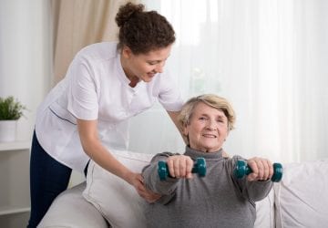 Old woman training with physiotherapist at home
