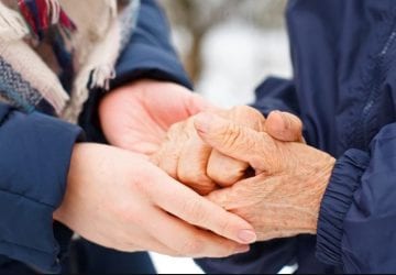 person holding the hands of an elderly person