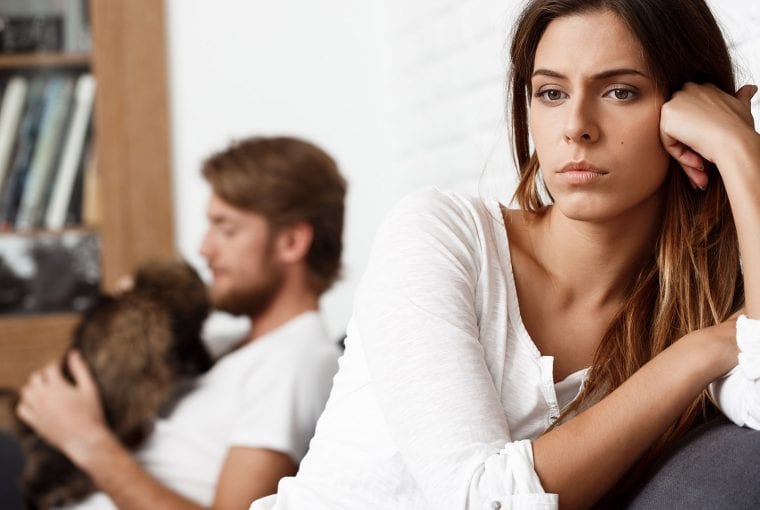 a woman in the foreground thinking and her male partner in the background
