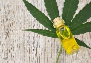 CBD oil on a table next to a cannabis leaf