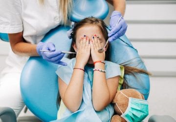 a girl covering her face while at the dentist