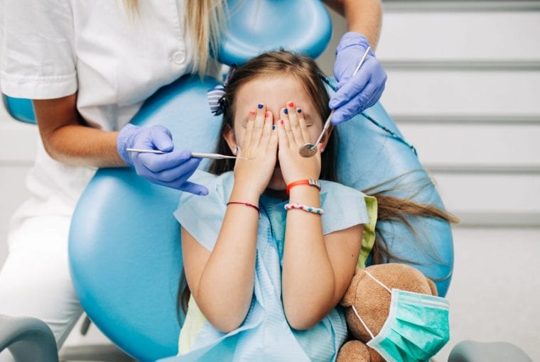 a girl covering her face while at the dentist