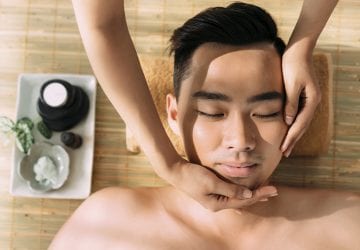 Young man receiving facial massage at the spa center, view from the top