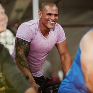 a man smiling while ridding in a spin bike class
