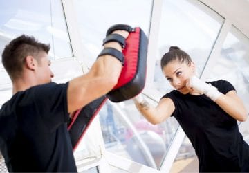 Woman hitting boxing pads with her trainer