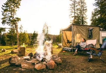woman sitting in front of a fire at a campsite