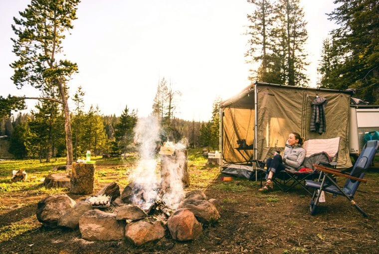 woman sitting in front of a fire at a campsite