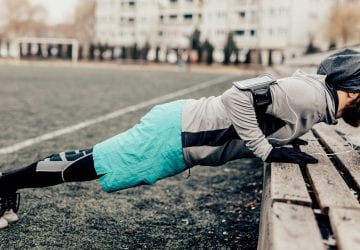 athlete doing push-ups on an outdoor bench