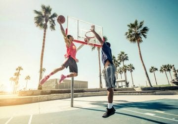 two men playing basketball outdoors
