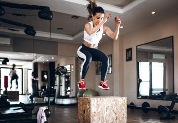 a woman doing box jumps at the gym