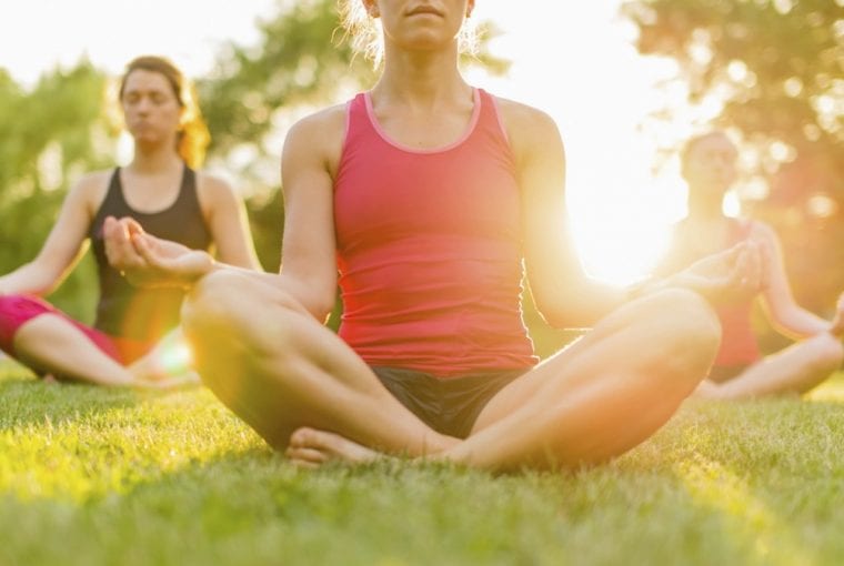 women sitting outdoors practicing yoga